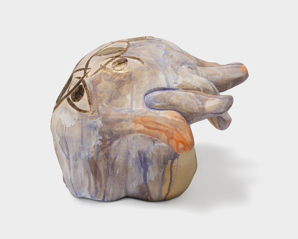 A ceramic sculpture with interlocked hands covered in streaking blue and orange glaze with golden painted eyes on the back of the hands.