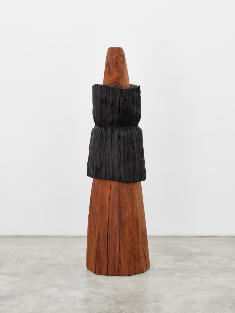 An elongated wooden cone shaped sculpture with a long black wooden carving fitted around its center.