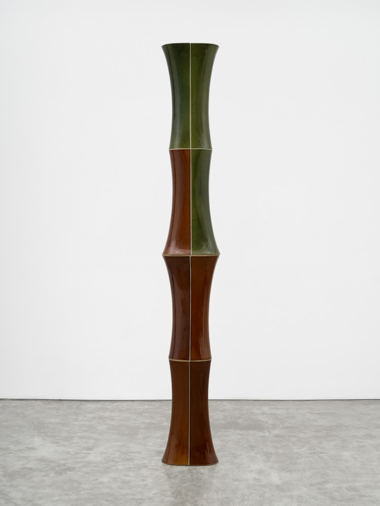 A freestanding ceramic sculpture with green and brown composite sloping parts.