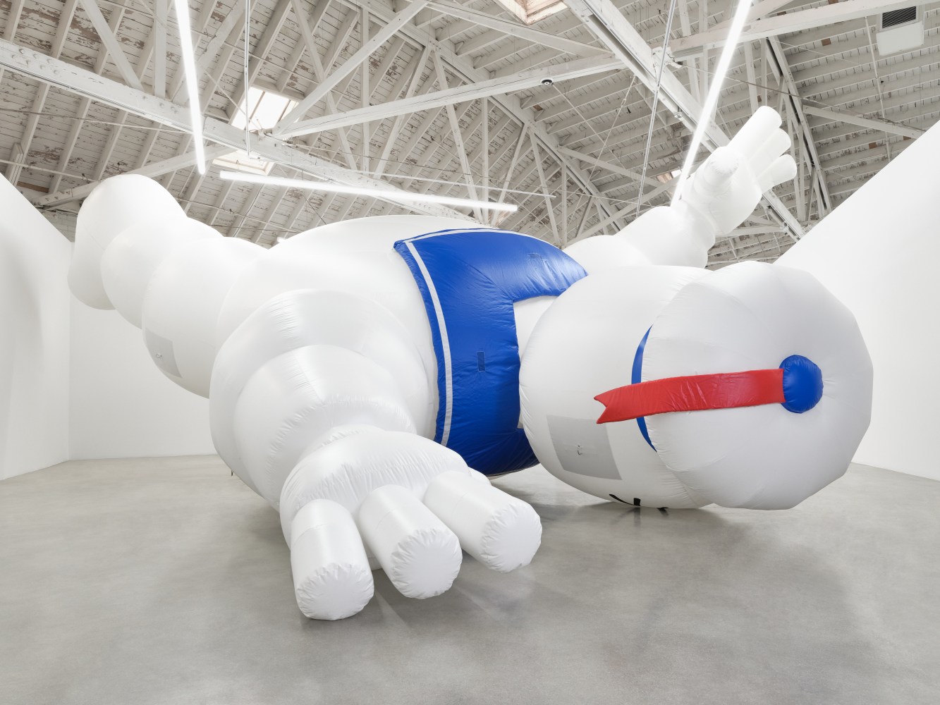 A 30 foot long and 21 foot high inflatable sculpture of the &quot;StayPuft&quot; character from the Ghostbusters movie franchise that who is white and bulbous with a sailor's collar and red tailed cap face down, feet in the air and left arm raised.