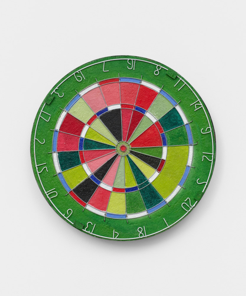 A dartboard painted in greens, reds, blues, black and pinks.