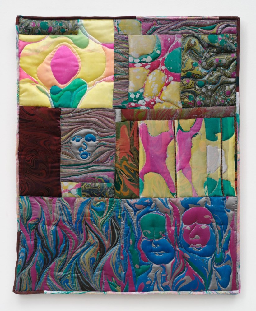 A rectangular sewn textile piece of marbled satin in yellow, pink, blue and magenta with three faces emerging from the patterning of the fabric.