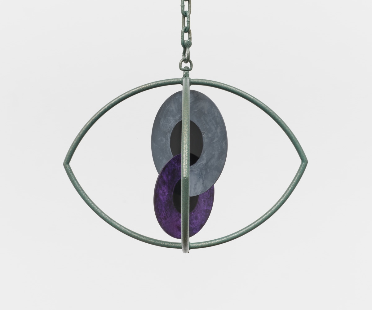 A hanging sculpture with two interlocking metal iris' inside a metal eye.