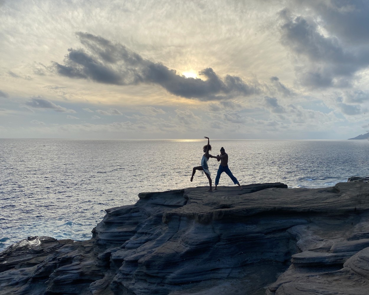 two dancers on the cliff, one lifting their leg