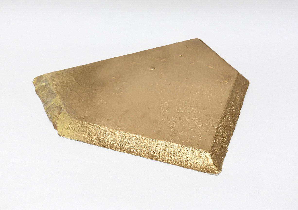 A gold sculpture in the shape of a baseball plate