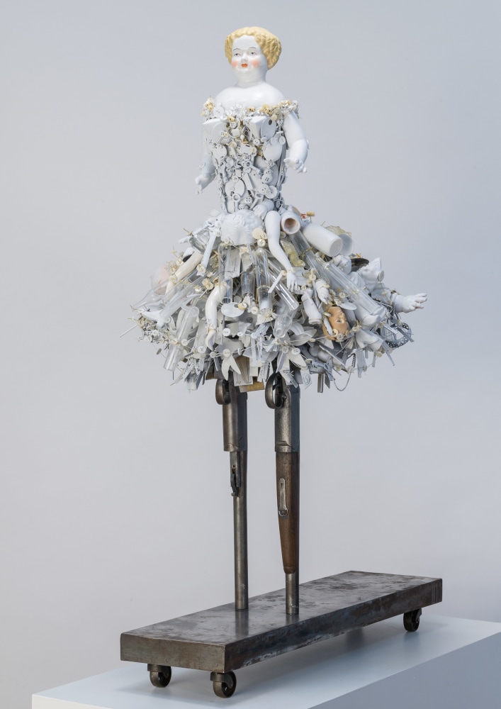 Karin Broker  Shotgun girl, 2021  shotguns, porcelain, ceramics, glass, button, wire, steel base  39 1/2 x 21 x 18 1/2 inches  $28,000