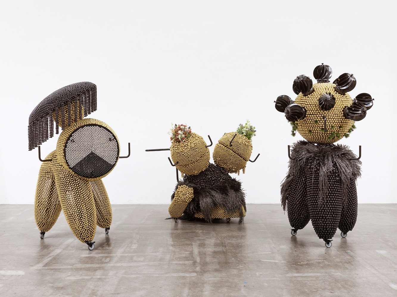 sonic intermediates &amp;ndash; triad walker trinity (sonic intermediate &amp;ndash; tripodal venting walker, sonic intermediate &amp;ndash; spinning mask on parasol walker, sonic intermediate &amp;ndash; botanical bi-headed creeping walker), 2020

set of 3 pieces. powder-coated steel frame, powder-coated mesh, powder-coated handles, casters, brass plated bells, black brass plated bells, metal rings, plastic twine, turbine vents, artificial plants, pine cones. powder-coated steel frame, powder-coated mesh, powder-coated handles, ball bearing, casters, nickel plated bells, brass plated bells, black brass plated bells, metal rings. powder-coated steel frame, powder-coated mesh, powder-coated handles, ball bearings, casters, brass plated bells, black brass plated bells, metal rings, plastic twine, artificial plants, multilayer foam

83.46 x 47.64 x 47.24 in

75.98 x 47.24 x 43.7 in

59.06 x 53.15 x 71.65 in