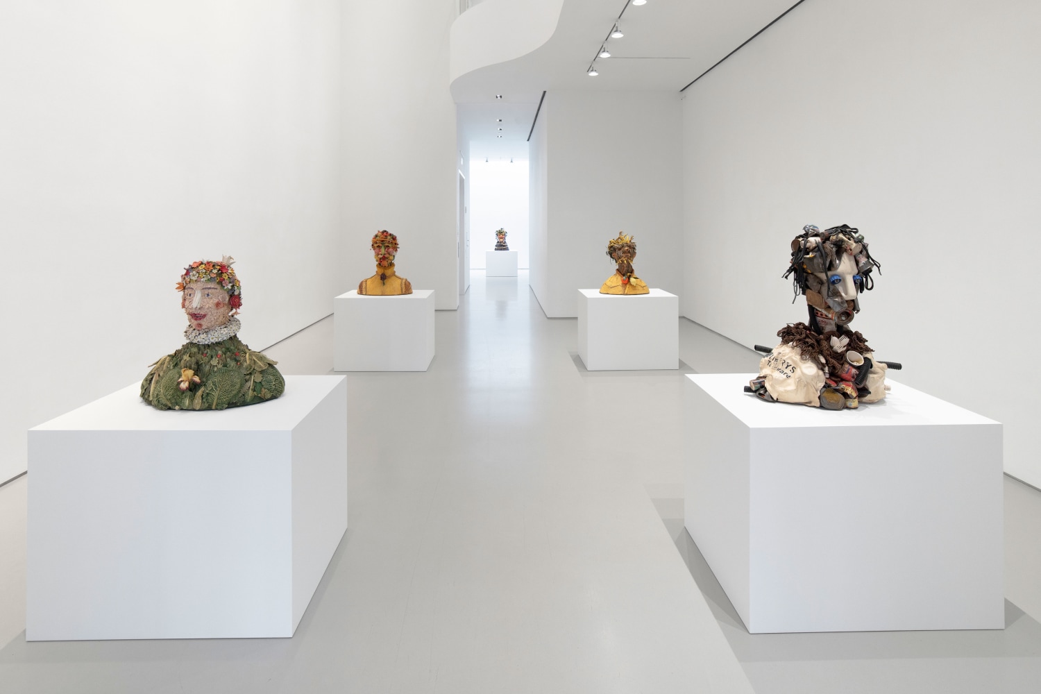 five bust sculptures installed in gallery on white pedestals
