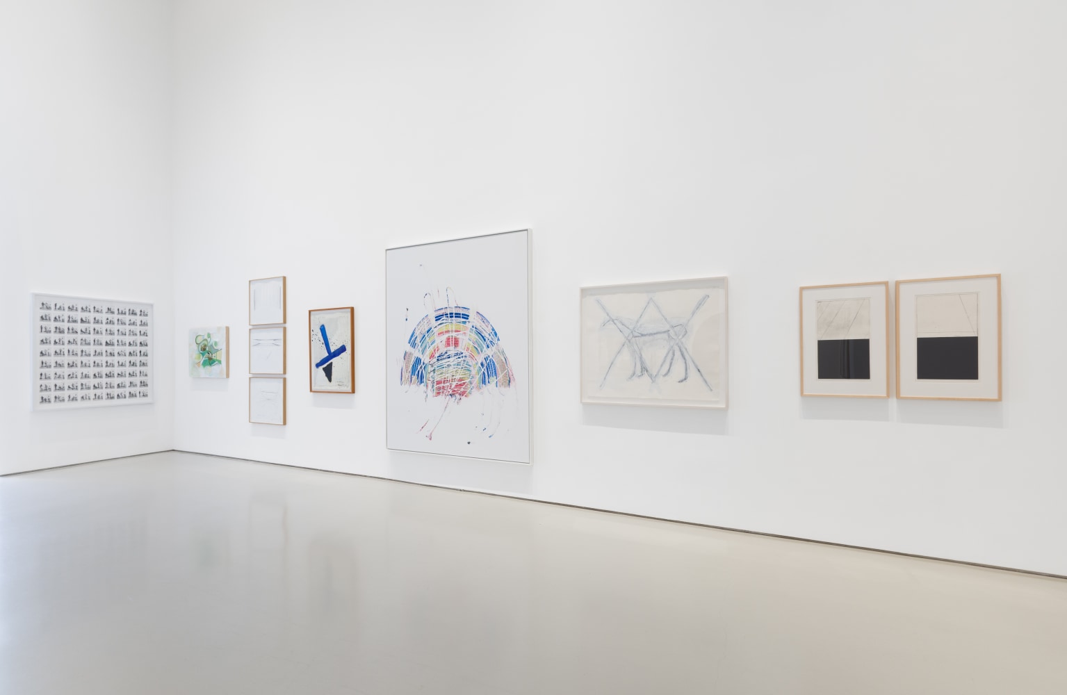 the corner of a gallery pictured with framed artworks of different sizes on the wall