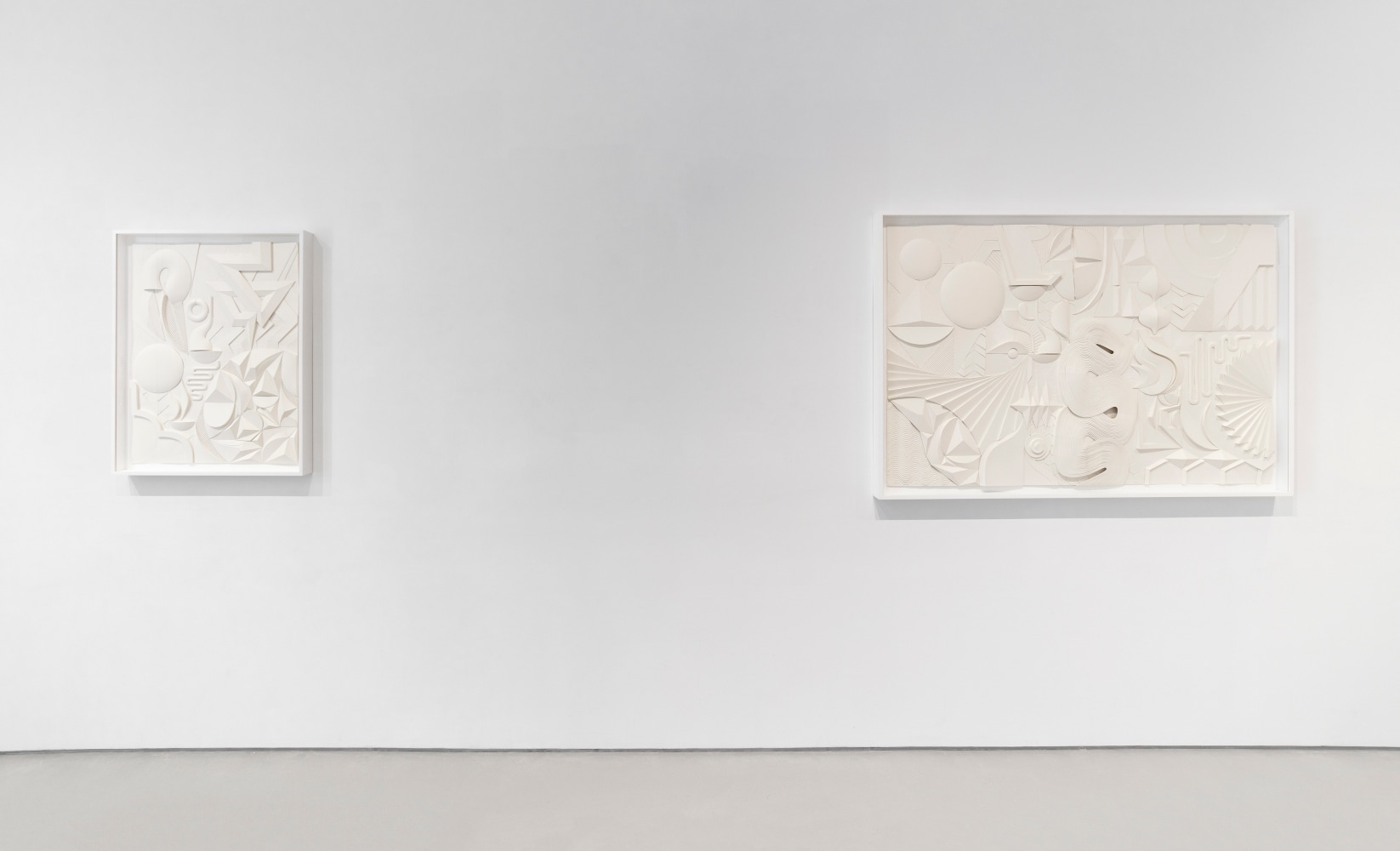Installation view of two white artworks on a white wall