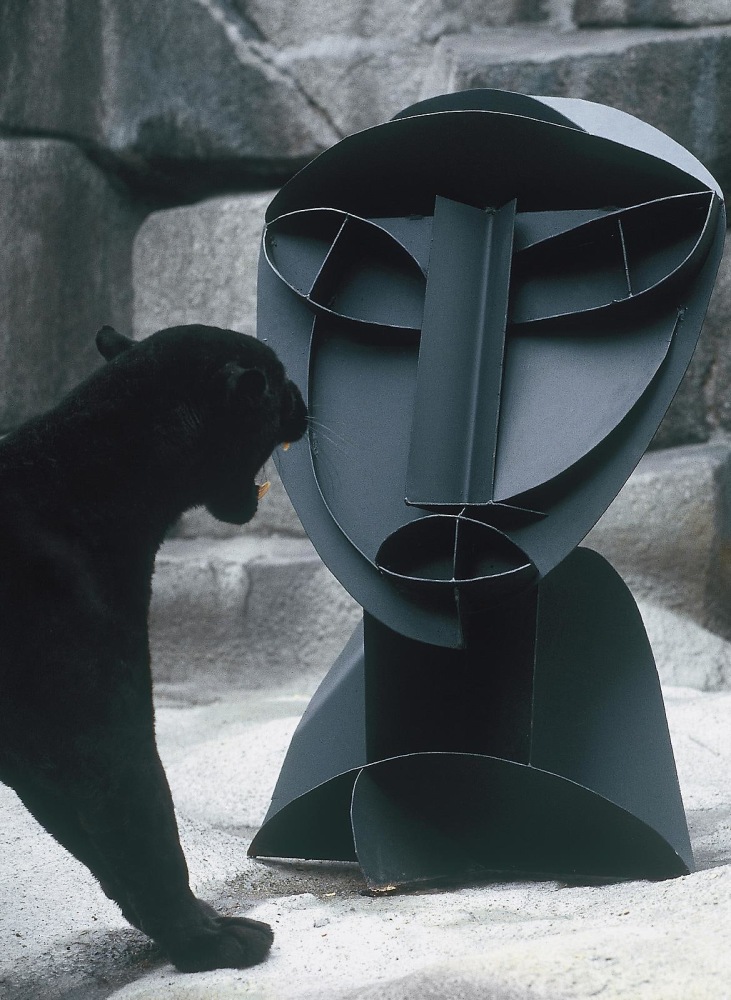 a panther growls at a large abstract sculpture of a human bust