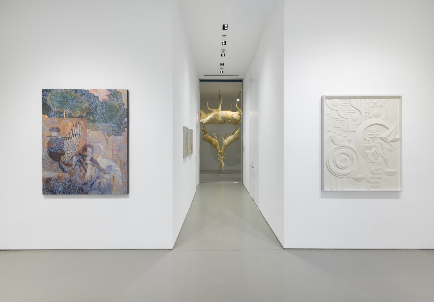 one artwork on each wall on either side of a hallway leading into a room with a sculpture of animals hanging from the ceiling