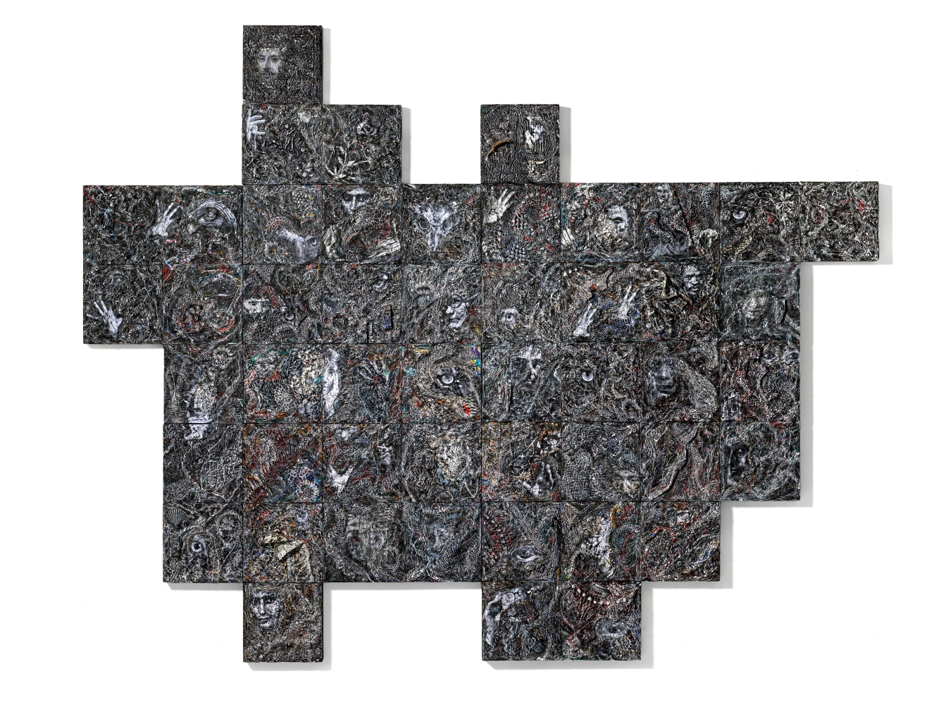 A dense relief constructed with myriad materials and images across wood blocks in overall grey tones.