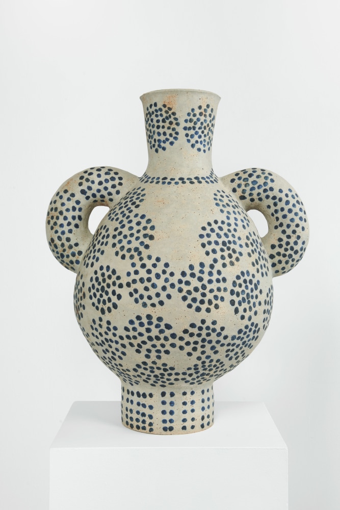 a bulbous ceramic vessel with two handles on either side, glazed with repeating circular patterns of blue dots