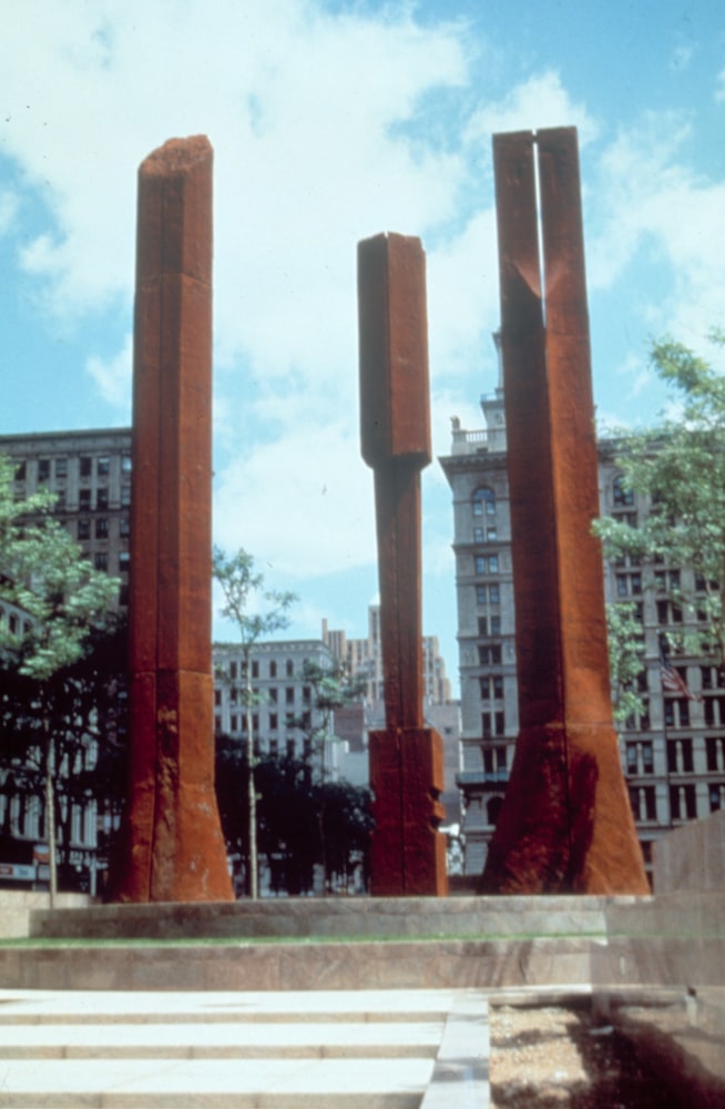 Three large-scale burnt orange columns installed in a federal plaza