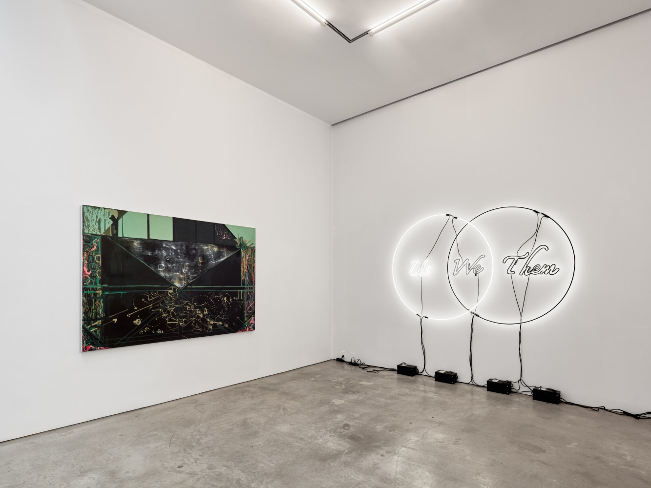 Installation view of &quot;Schema World as Diagram&quot; featuring a painting and a white neon sign of a venn diagram reading &quot;Us / We / Them.&quot;