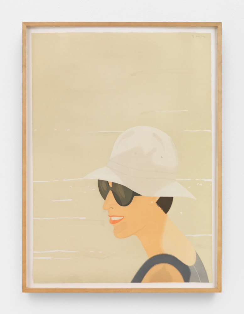 Framed color aquatint by Alex Katz of a smiling woman wearing a tan bucket and sunglasses against a sandy background