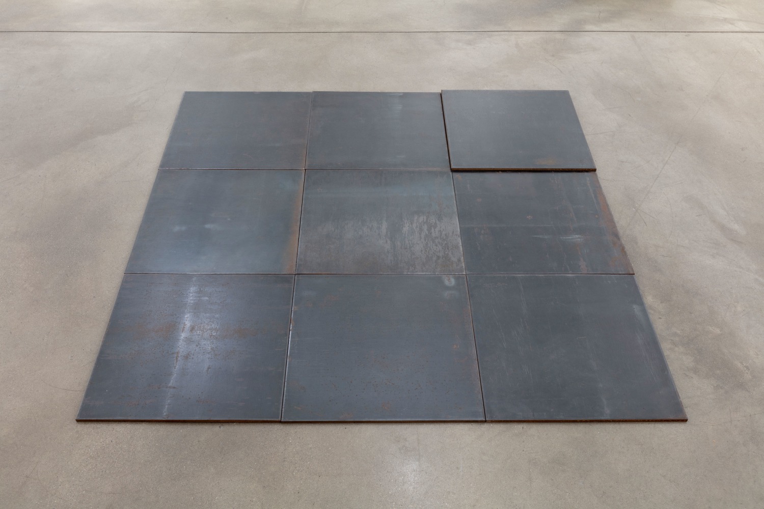 Carl Andre North-East Deck, Glarus, Switzerland 1993 hot-rolled steel 10 units: 9-unit square (3 x 3) on floor with tenth unit superimposed on north-east unit each: 1/4 x 19 3/4 x 19 3/4 in. (.6 x 50.2 x 50.2 cm) overall: 1/4 x 59 x 59 in. (.6 x 149.9 x 149.9 cm)