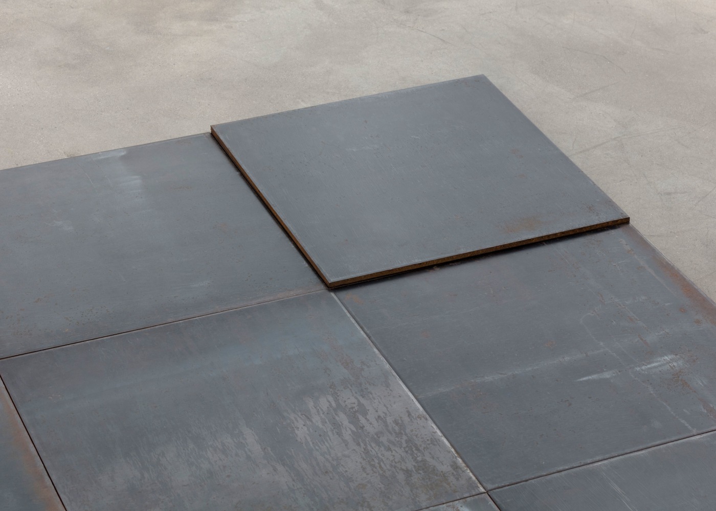 Carl Andre
North-East Deck, Glarus, Switzerland 1993
hot-rolled steel
10 units: 9-unit square (3 x 3) on floor with tenth unit superimposed on north-east unit
each: 1/4 x 19 3/4 x 19 3/4 in. (.6 x 50.2 x 50.2 cm)
overall: 1/4 x 59 x 59 in. (.6 x 149.9 x 149.9 cm)