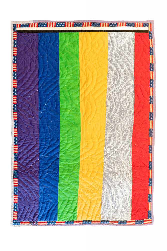 A rainbow quilt framed in an American Flag border