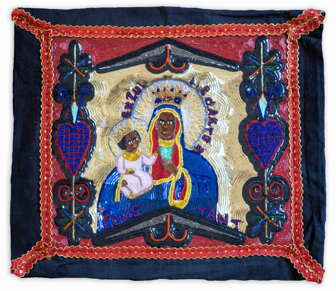 A beaded piece of a woman saint holding a child surrounded by hearts