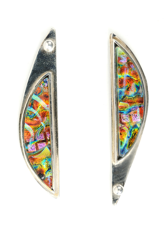 Symmetry is Overrated
The slender arcs of dichroic glass are set in Argentium Sterling silver. A dot on top of one earring and on the bottom of the other lends a unique and whimsical accent.
.33&amp;quot; x 1.25&amp;quot; x .25&amp;quot;
2020