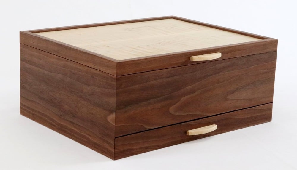 Watch collector&amp;#39;s box
Walnut box with curly maple lid panel design to store 12 fine watches and a pull-out drawer with interior dividers for cufflinks and watch bands. The interior bottom is lined with black velvet. The box sides feature continuous grain at all four corners.
13&amp;quot; x 5&amp;quot; x 6&amp;quot;