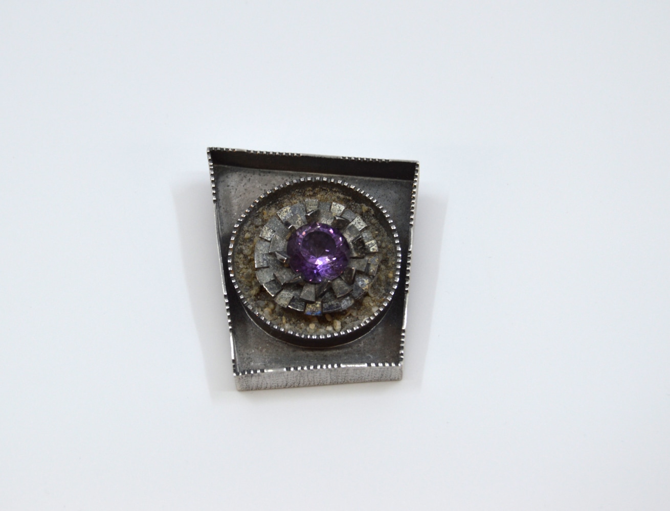 Margery Cooper, At Odds, Brooch  1.75&quot; x 1.5&quot;  Sterling Silver, Amethyst, Beach Sand, Gosiba Patina