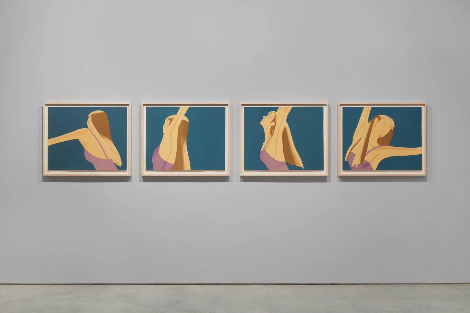 Installation view featuring four framed photographs by Alex Katz of woman wearing a purple leotard against a blue background dancing in motion