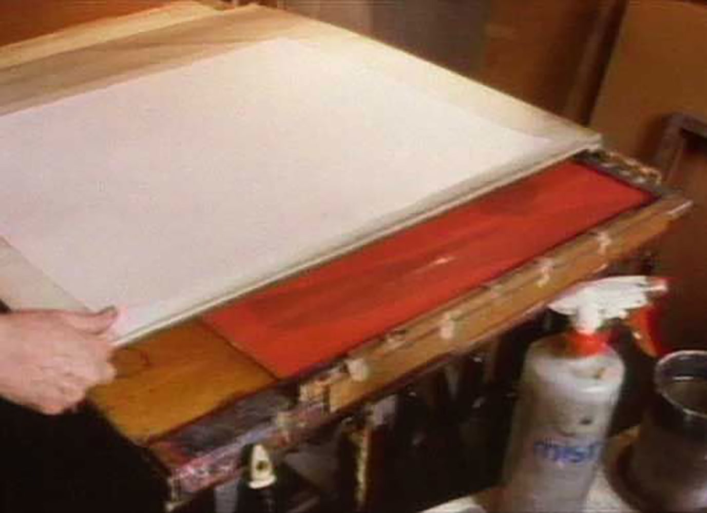 4.&amp;nbsp;After each template is painted, it is placed into register and Glankoff slides a panel carrying the Japanese paper panel across the surface of the board. In this photograph, Glankoff has painted this template with an overall red ground color - the first of many layers of color.