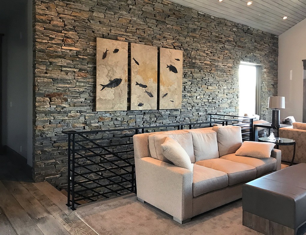 A fossil triptych mural containing large and small fossil fish hangs on a stone wall in a Park City home