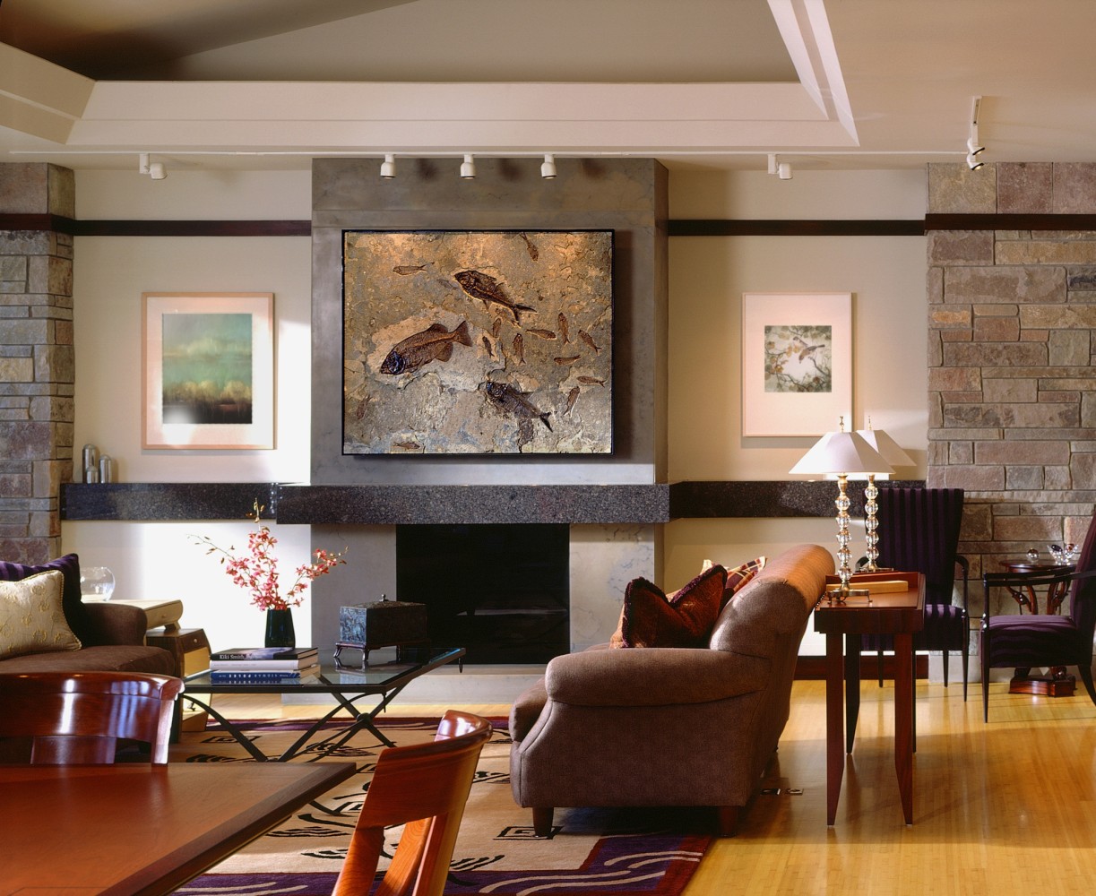 A contemporary living room features a 4' x 6' dark limestone fossil mural, hanging above a stone fireplace