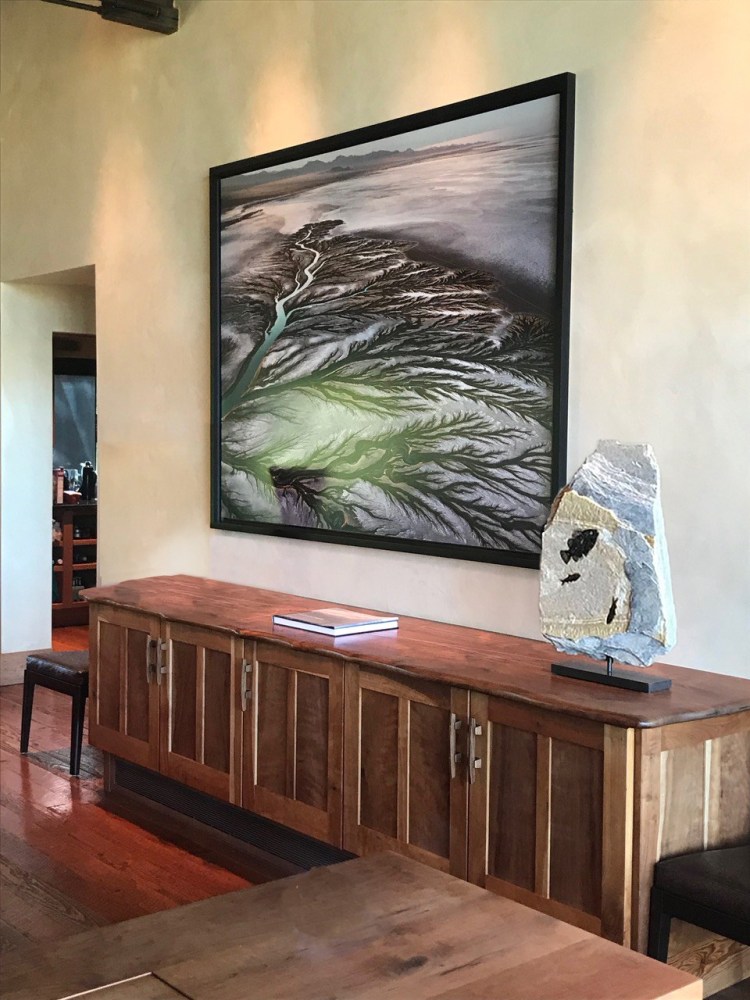 A fossil stone sculpture containing large and small fossil fish sits along side an Edward Burtynsky photograph