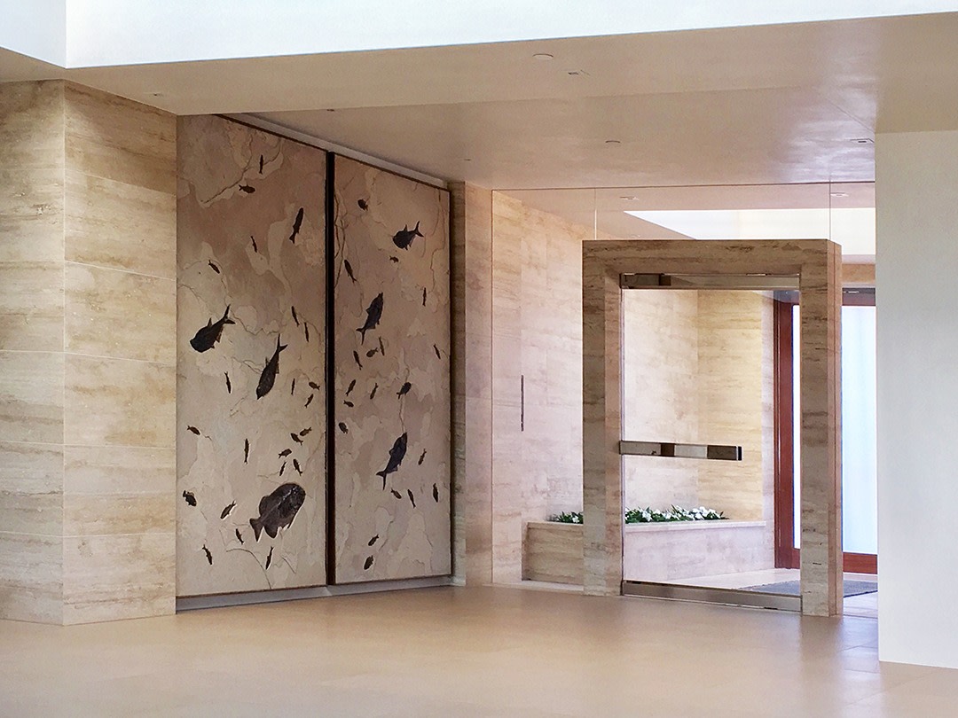 A giant fossil duptich mural containing large and small fossil fish sits just inside the entryway of a modern home