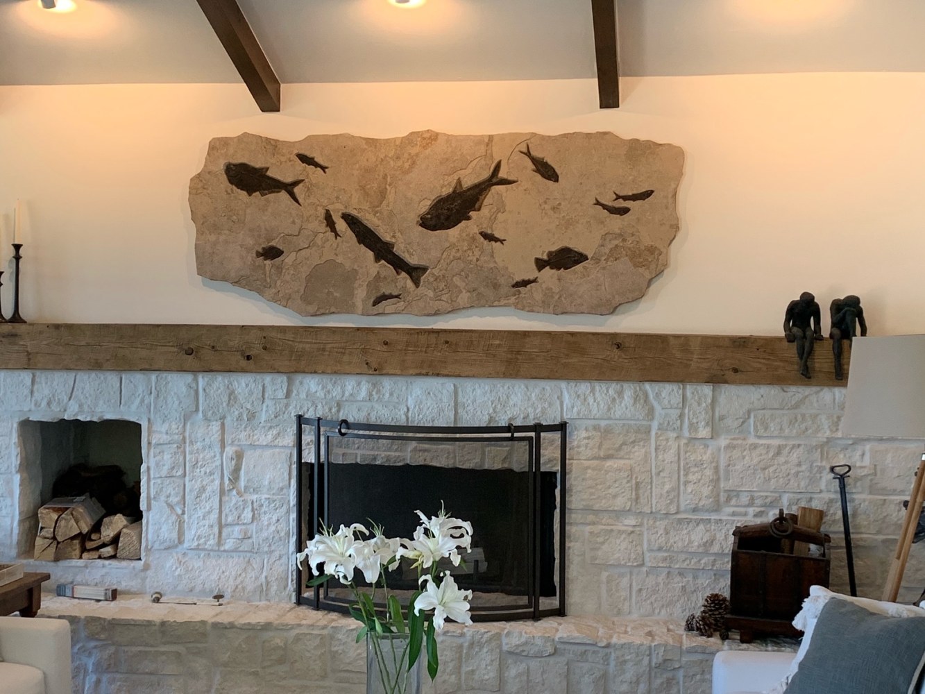 A large irregularly shaped fossil mural hangs above a stone fireplace