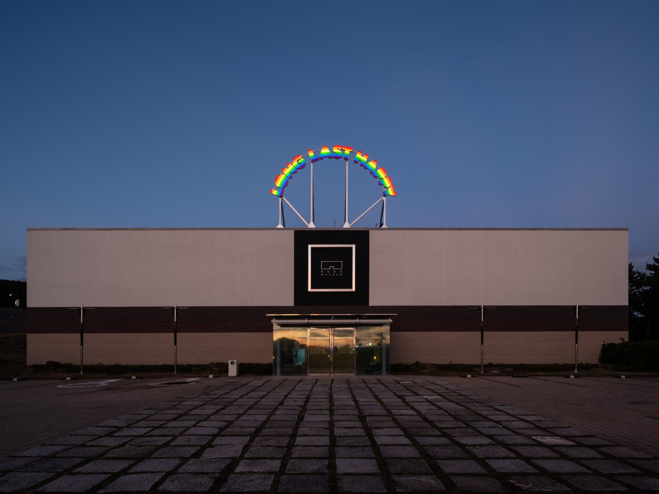 Installation view of outdoor neon sign saying long last happy by Ugo Rondinone