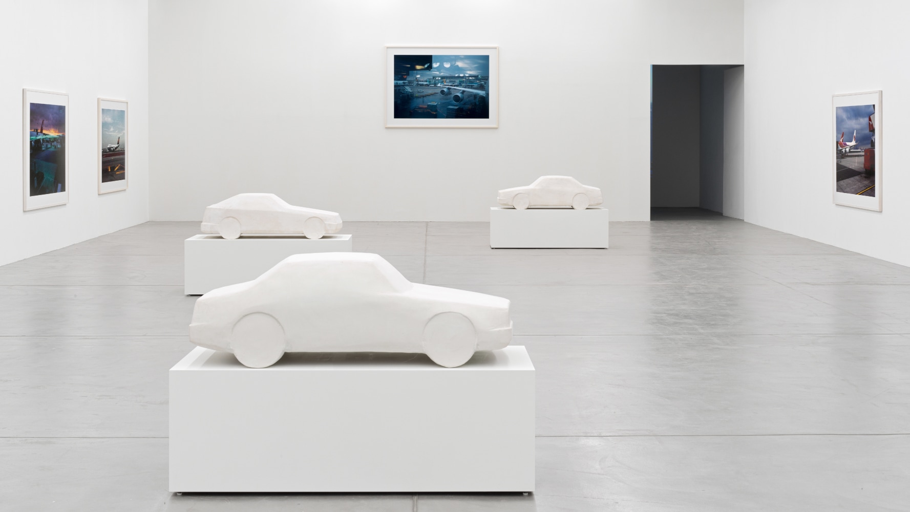 installation view of photographs of airports and car sculptures by Peter Fischli and David Weiss