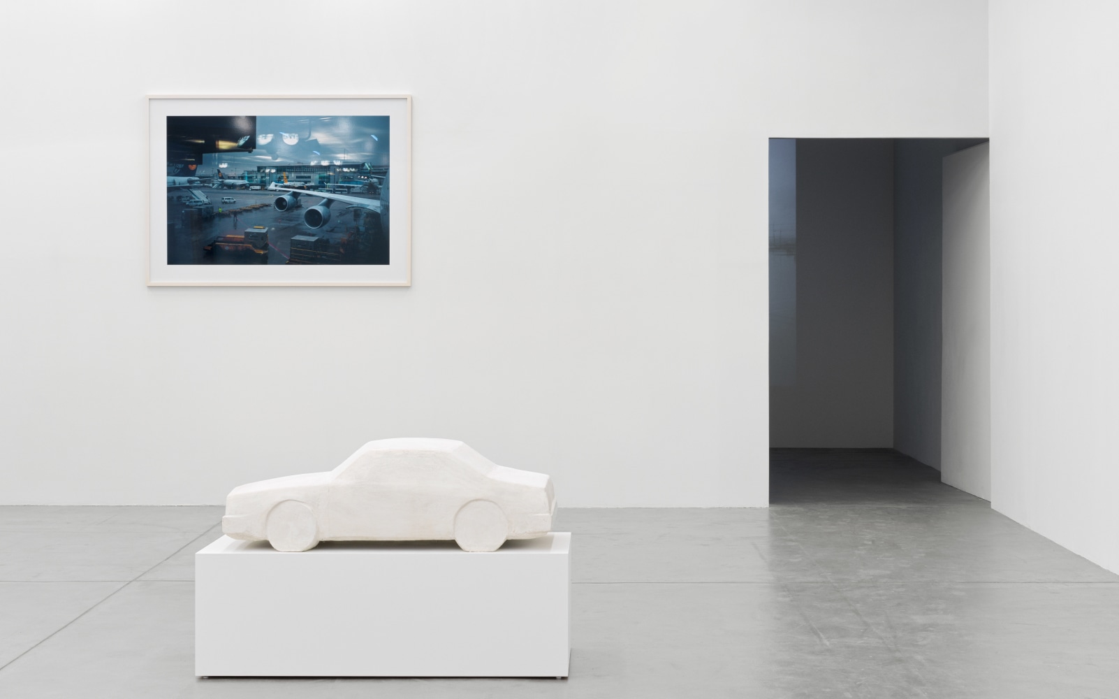 installation view of photographs of airports and car sculptures by Peter Fischli and David Weiss