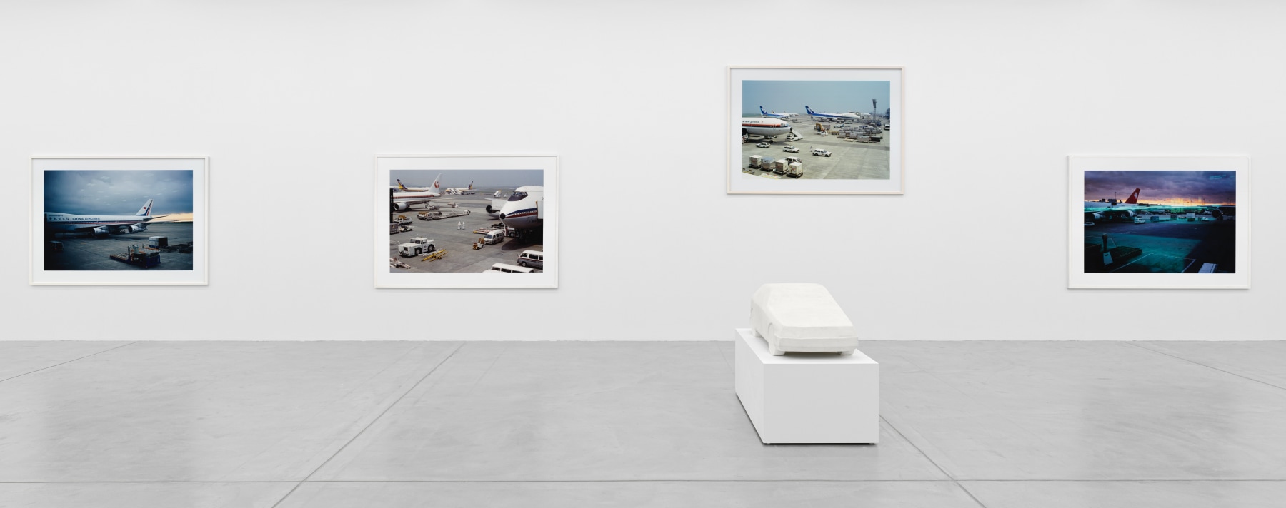 installation view of photographs of airports and car sculptures by Peter Fischli and David Weiss