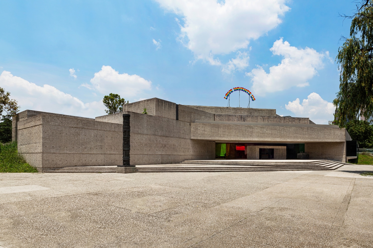 Installation view of colorful clown sculptures and rainbow colored windows by Ugo Rondinone