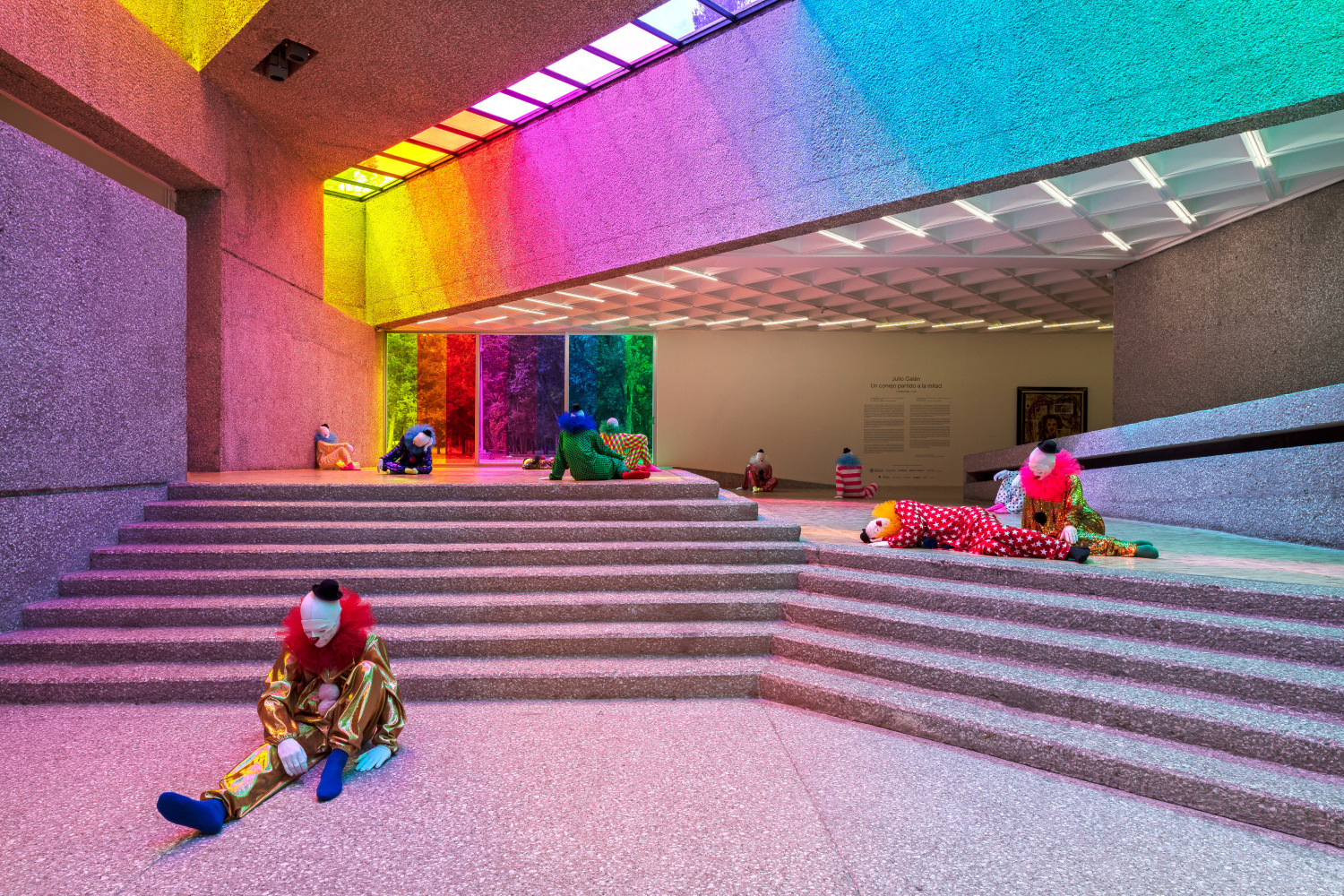 Installation view of colorful clown sculptures and rainbow colored windows by Ugo Rondinone
