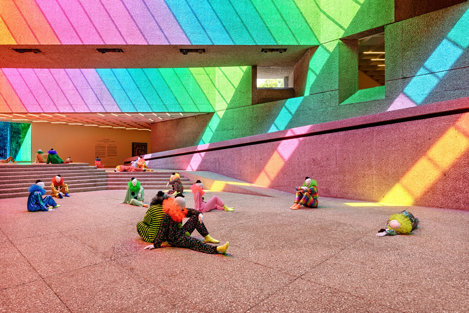 Installation view of colorful clown sculptures and rainbow colored windows by Ugo Rondinone
