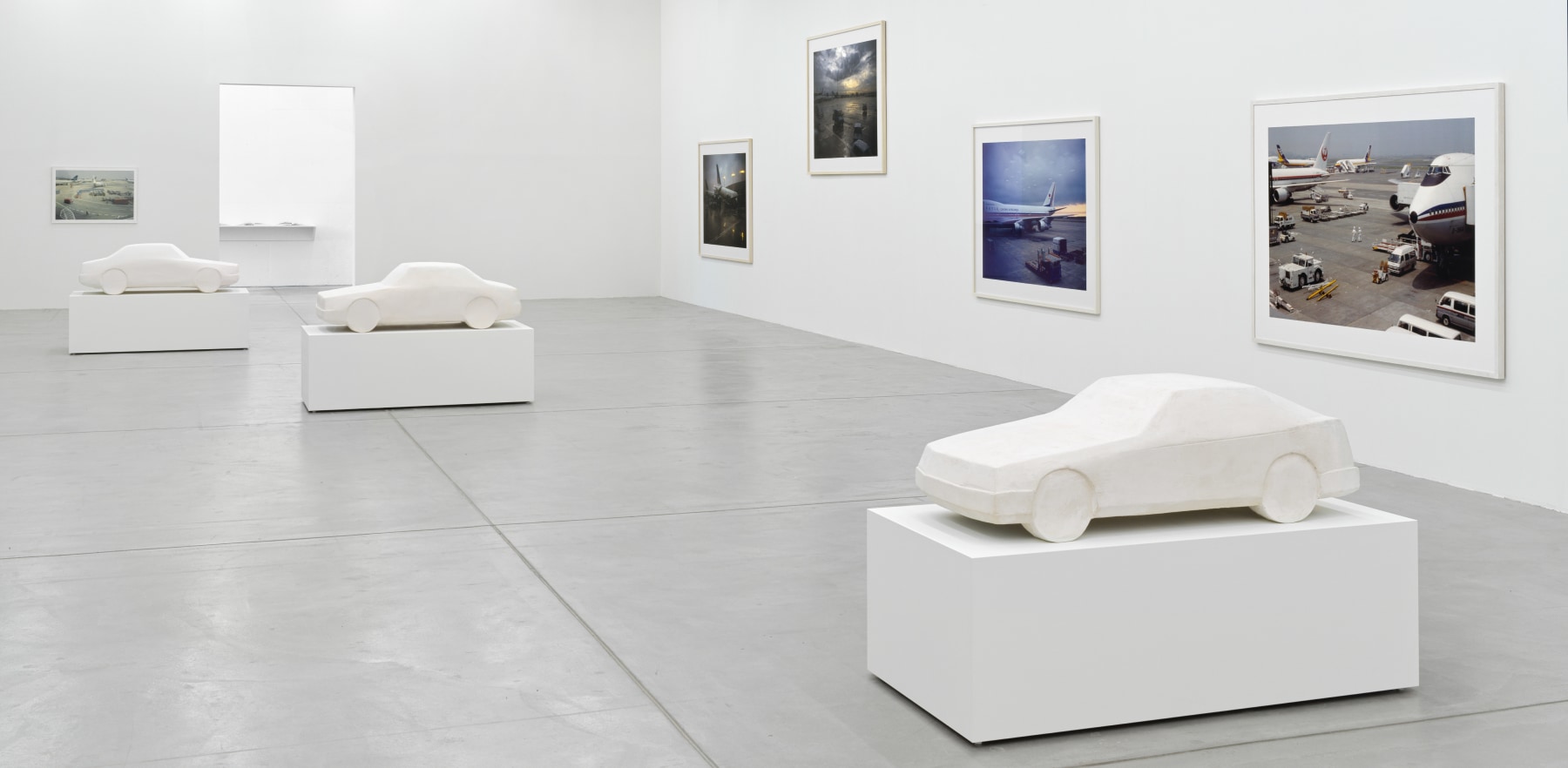 installation view of photographs of airports and car sculptures by Peter Fischli and David Weiss