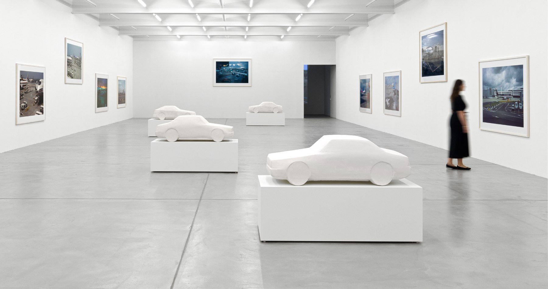 installation view of photographs of airports and car sculptures by Peter Fischli and David Weiss