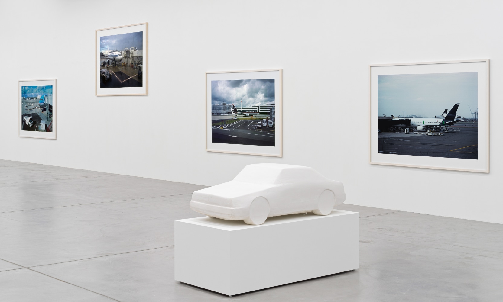 installation view of photographs of airports and car sculptures by Peter Fischli and David Weiss