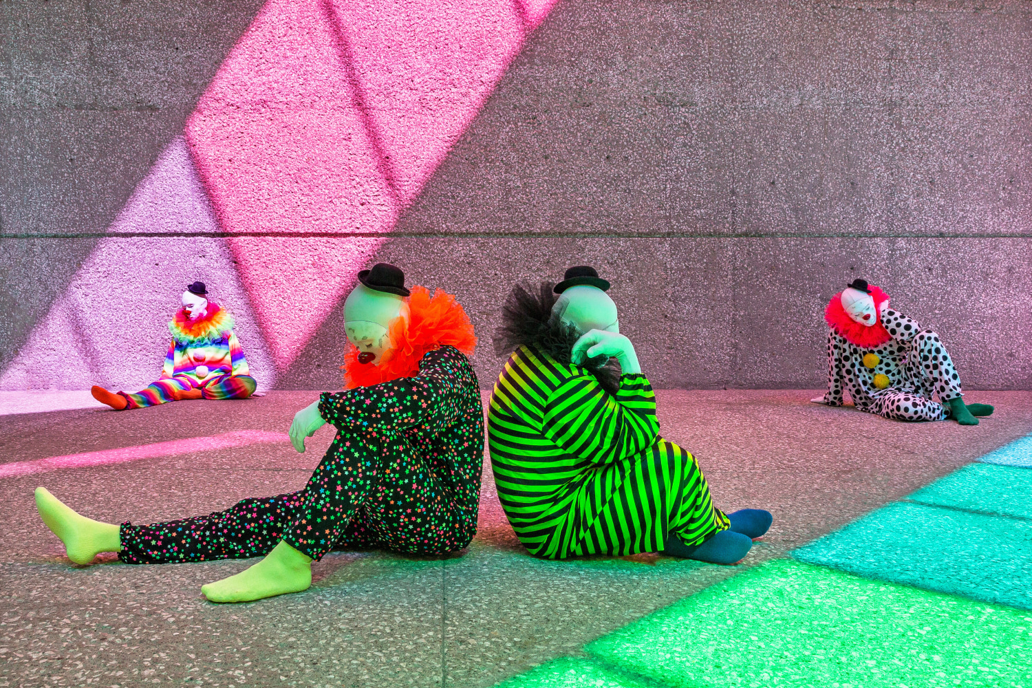 Installation view of colorful clown sculptures and rainbow colored windows by Ugo Rondinone
