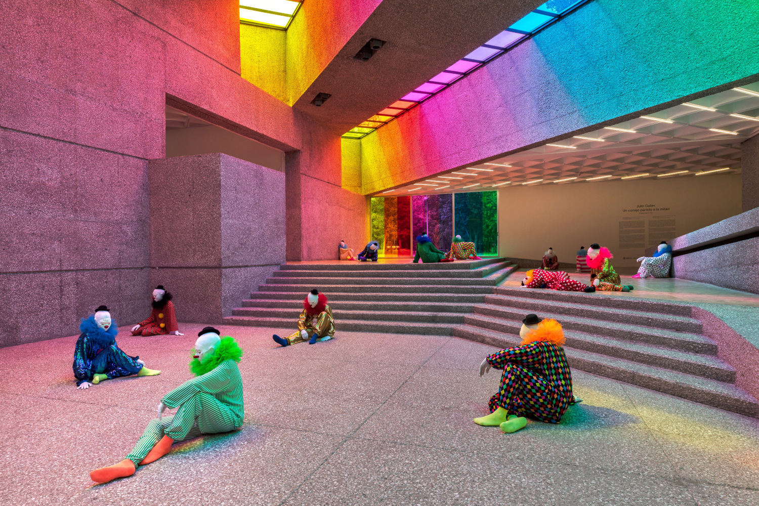 Installation view of colorful clown sculptures and rainbow colored windows by Ugo Rondinone