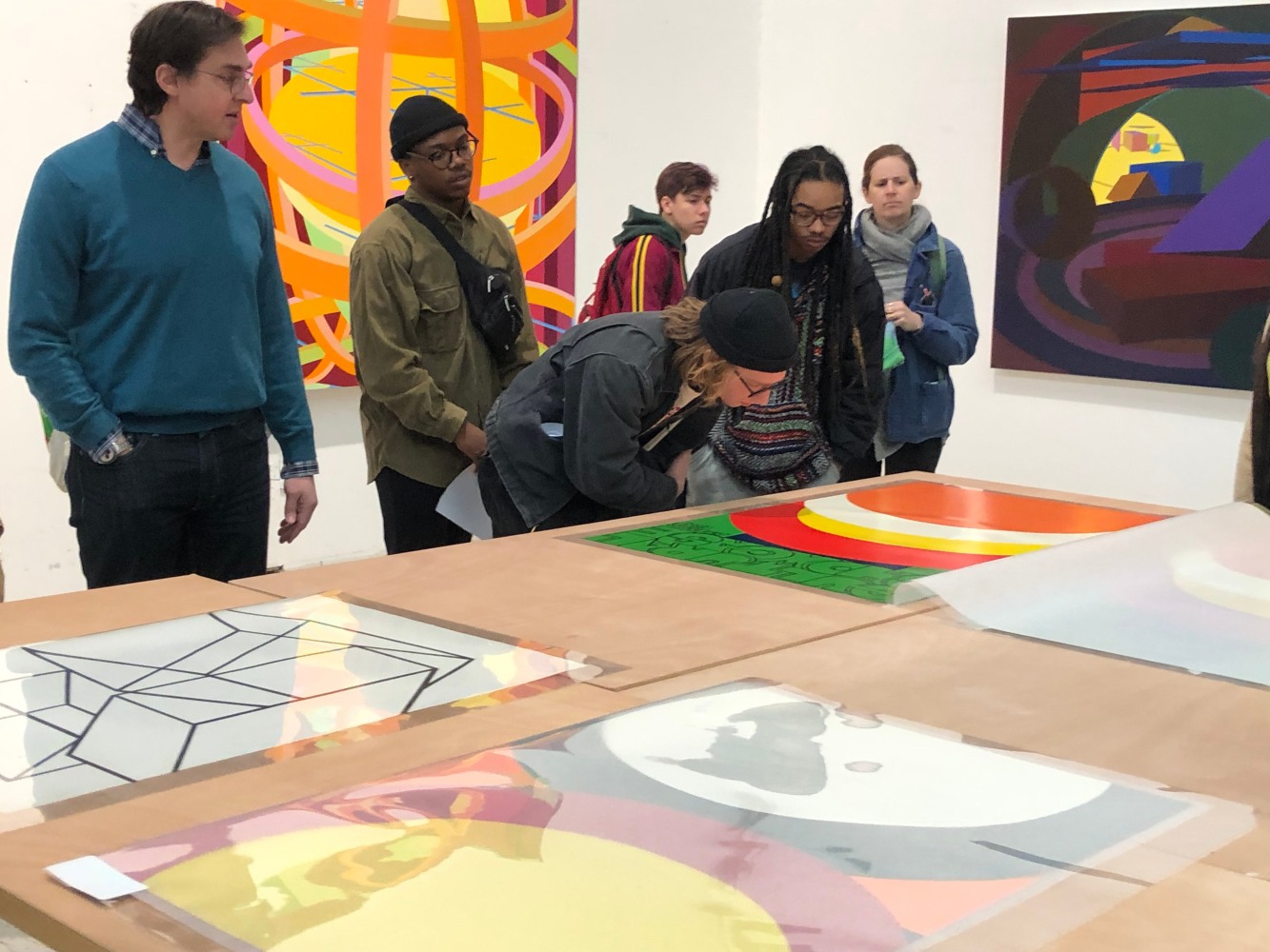 A group of students discuss colorful abstract prints and paintings by Al Held.