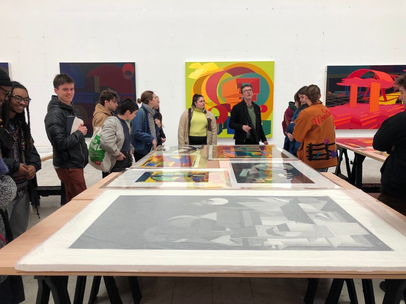 A group of students discuss colorful abstract prints and paintings by Al Held.