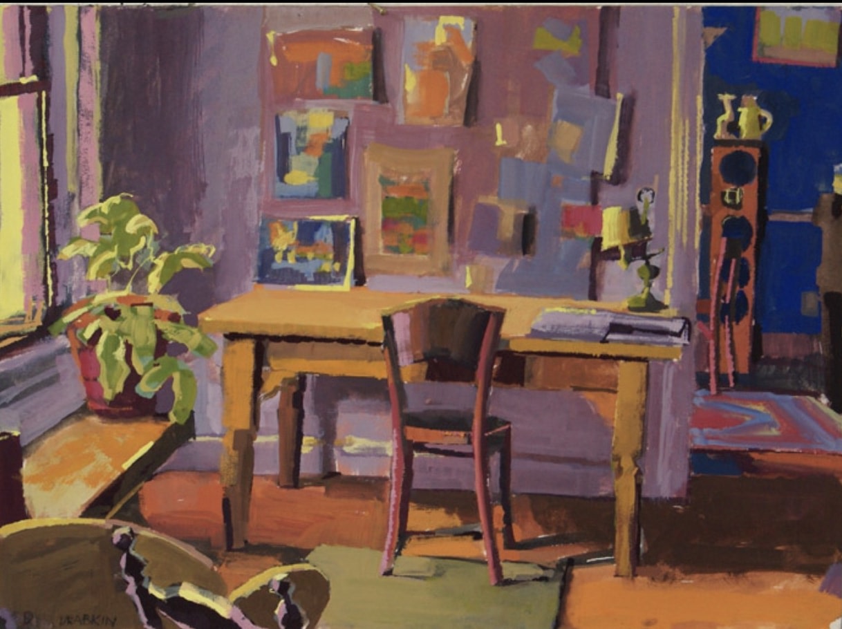art studio interior with a table and chair and a view into another room in bright primary colors